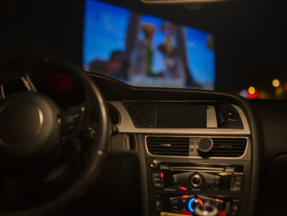 View inside of car and window where drive inn movie is being shown.