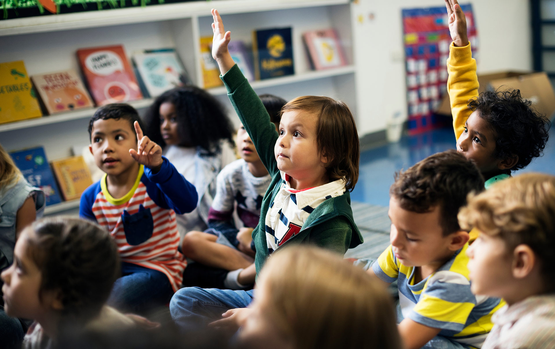 Group of elementary students with one child's hand raised.